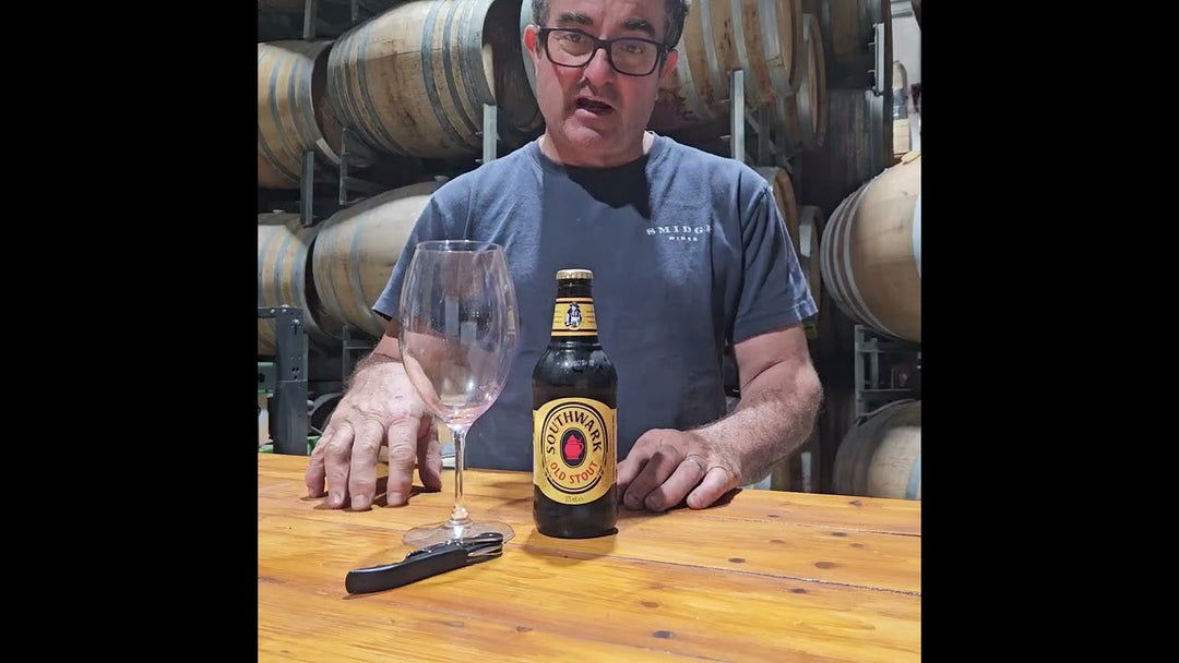 Matt Wenk holding a glass of dark Southwark Old Stout with a creamy head in a wine glass during a tasting.